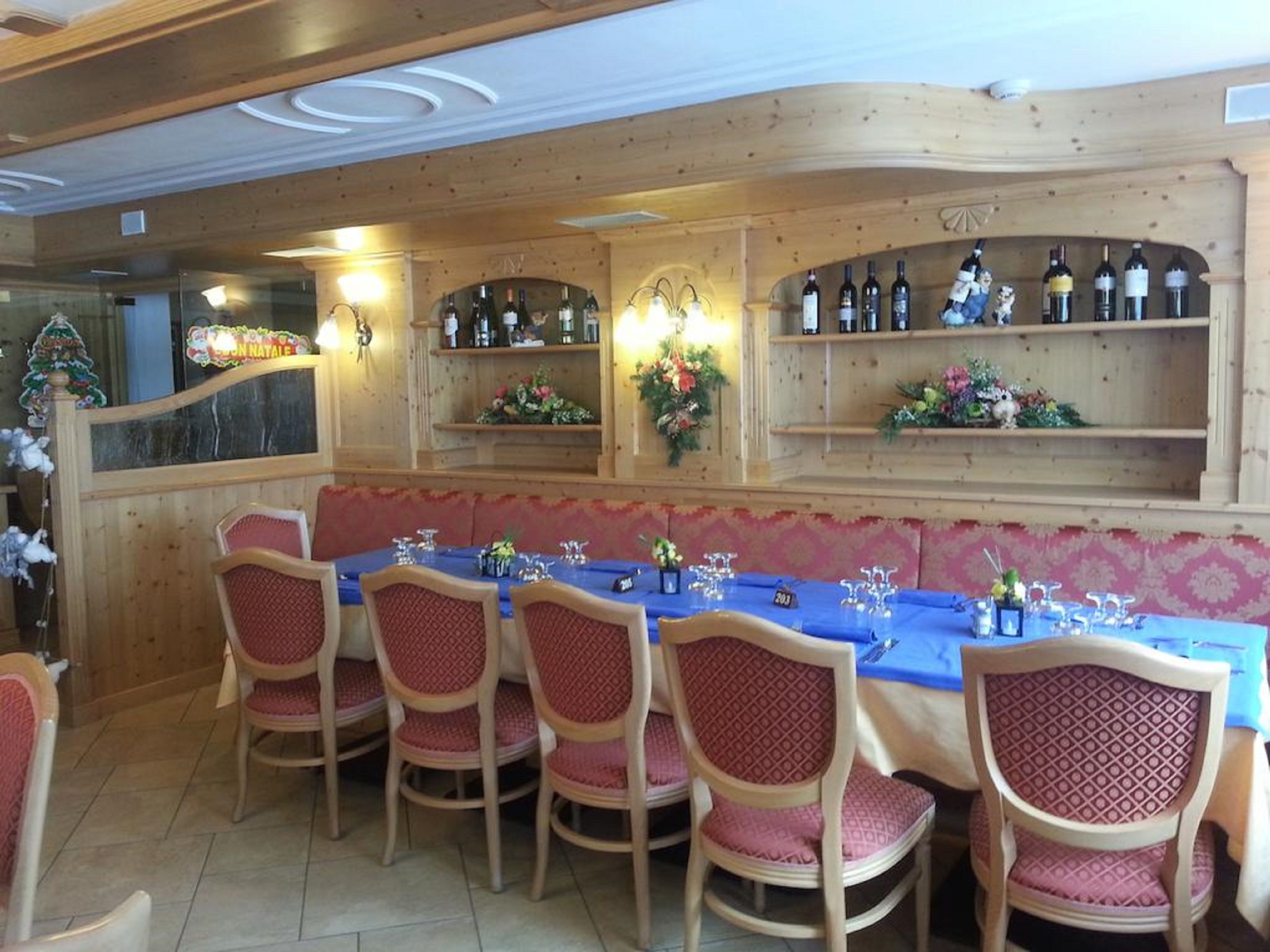 A restaurant with a long table set for dining, wooden walls, and shelves with bottles.