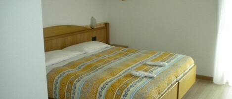 A single bed with a wooden frame and a patterned bedspread.