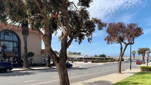 A street with trees, a building with a red roof, and parked cars. - Avalon Inn Downtown Morro Bay (Morro Bay)