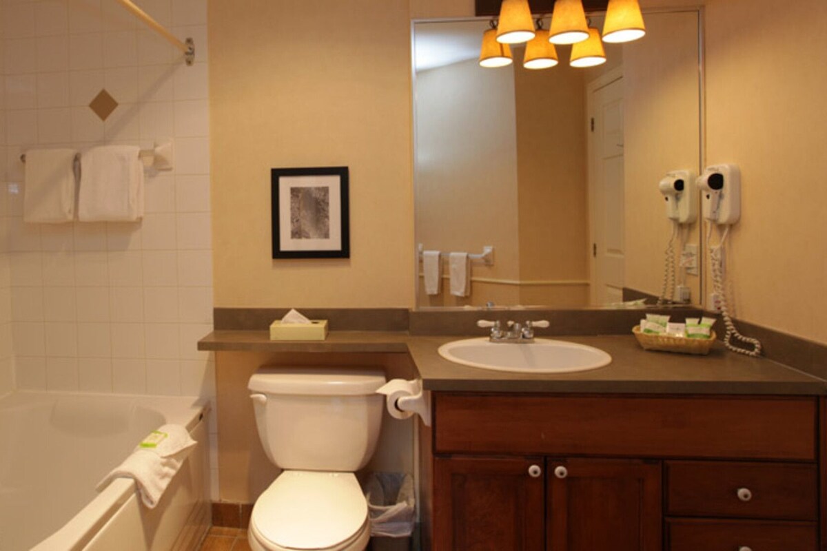 A bathroom with a bathtub, toilet, sink, and a mirror.