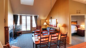 A hotel room with a dining area, a sofa, a TV, and a bed. - Place St-Bernard (Mont-Tremblant)