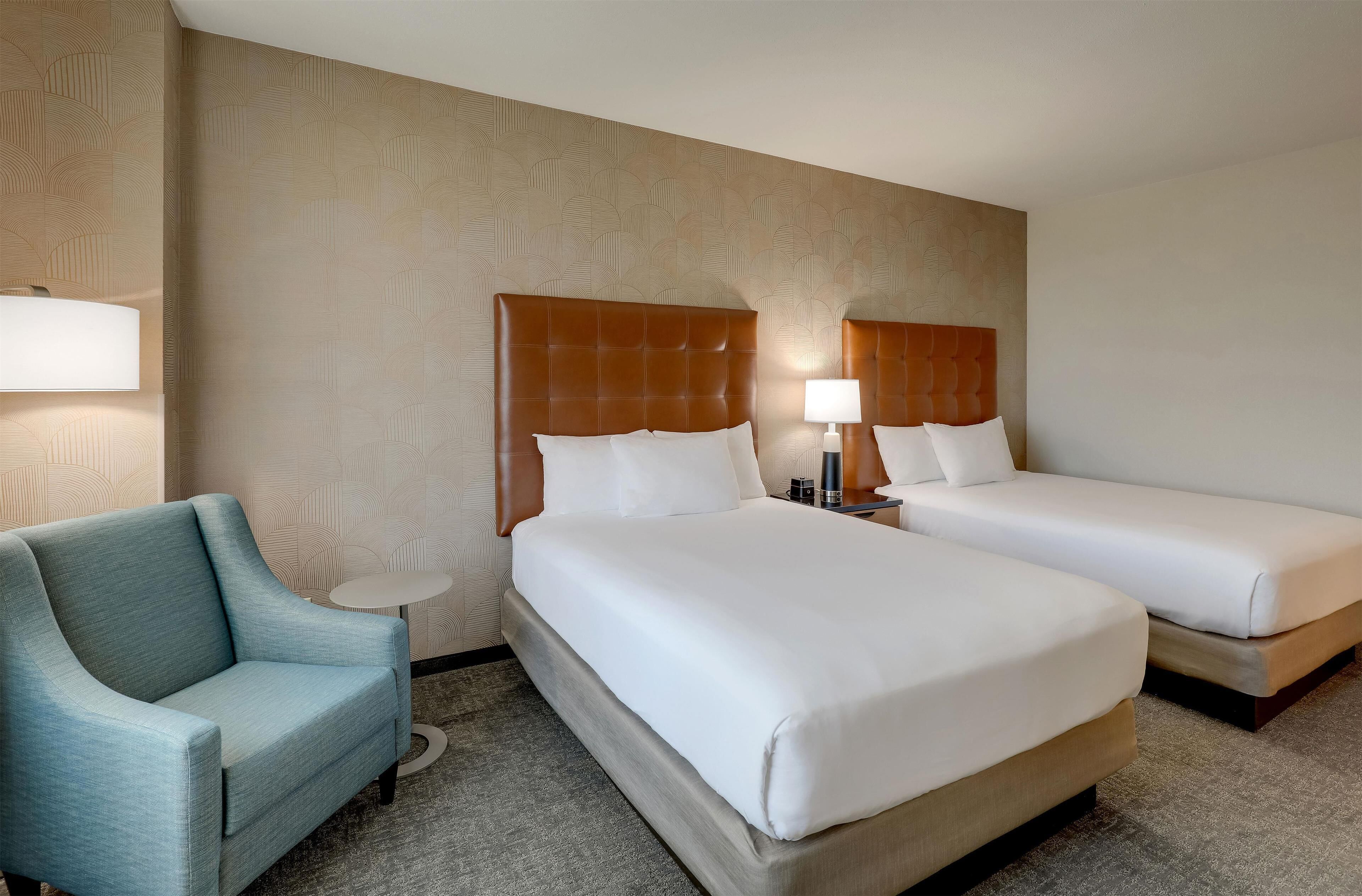 Quarto de hotel com duas camas, um sofá e uma pequena mesa.