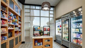 En liten kiosk där man kan köpa snacks och drycker, med hyllor fyllda med olika sorters snacks och drycker, en mikrovågsugn och ett kylskåp.