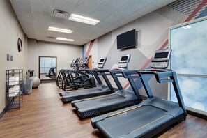 A gym with treadmills, exercise balls, and a mirrored wall.