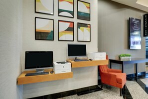 A reception desk with two monitors, a printer, and a keyboard. There are framed abstract artworks on the wall above. - Drury Inn & Suites Montgomery (Montgomery)