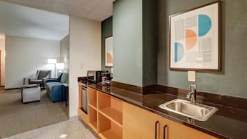 A modern kitchen with a black countertop, stainless steel sink, and wooden cabinets.