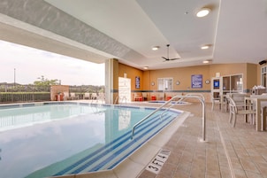 Una piscina con solárium empedrado, ventilador de techo y vistas del entorno.