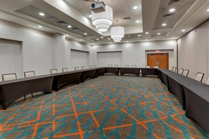 Un salón de conferencias con una mesa larga, sillas y una alfombra estampada.