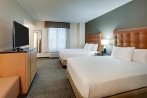 Une chambre d’hôtel avec deux lits, une télévision, un bureau et un miroir.