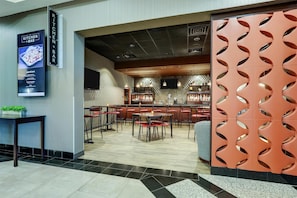 Un restaurant doté d’un bar, de nombreuses tables et chaises, et d’un mur décoratif orné de motifs découpés.