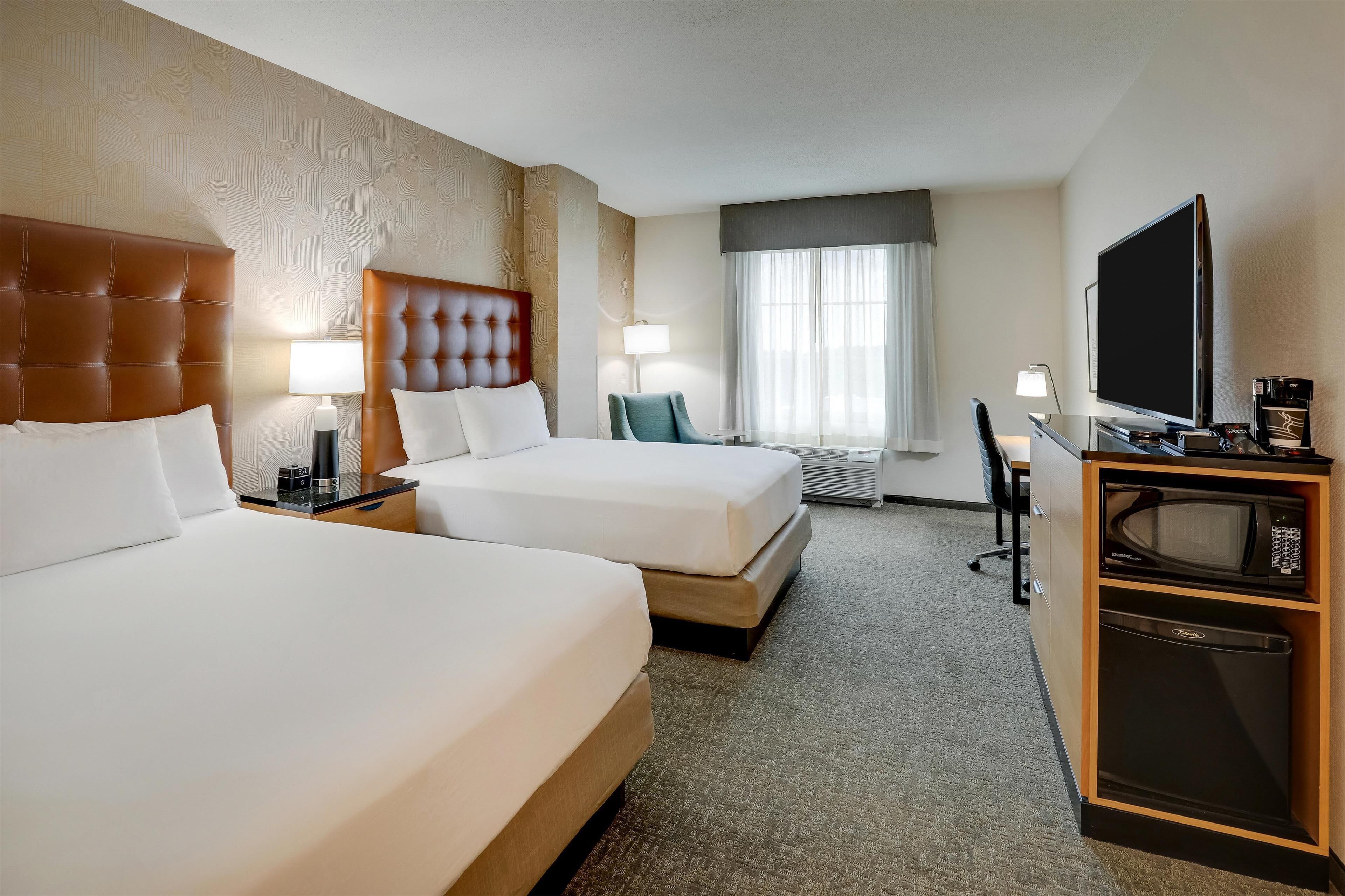 A hotel room with two beds, a television, a coffee maker, and a microwave.