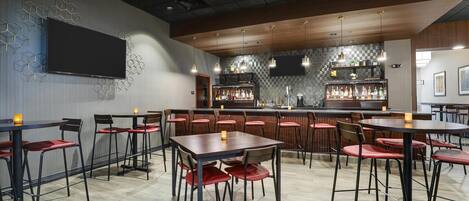 A modern bar area with multiple seating options, including tables and chairs, and a bar counter with a variety of bottles.