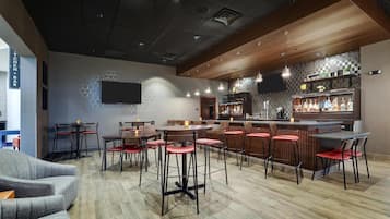 A modern bar area with wooden accents, bar stools, and a flat-screen TV mounted on the wall.