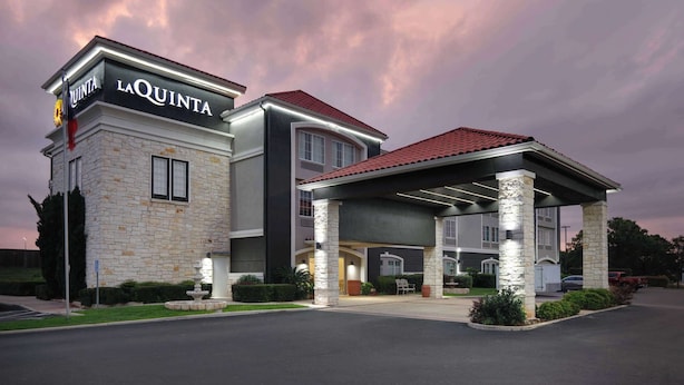 A hotel with a stone facade, a covered entrance, and a sign reading "LA QUINTA". - La Quinta Inn & Suites by Wyndham Fredericksburg (Fredericksburg)