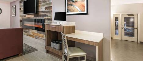 Un salon moderne avec une cheminée, un téléviseur à écran plat, un bureau avec une chaise et un tableau encadré au mur.