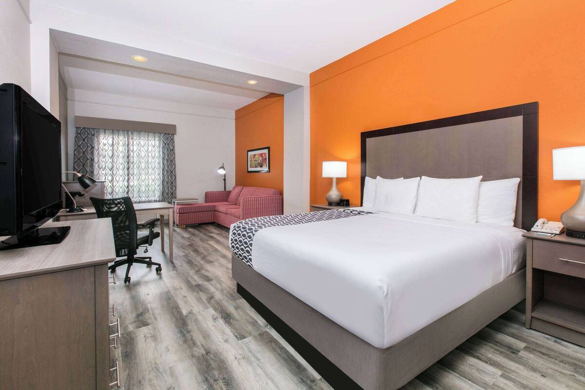 Habitación de hotel con una cama grande, un escritorio con computadora, una silla y un televisor.