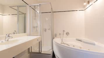 Un baño moderno con ducha de vidrio, tocador doble y bañera independiente.