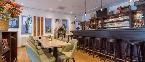 Um restaurante com área de bar, mesas de madeira e banquetas.