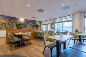Un restaurante con cabinas y mesas, suelo de madera y un mural en la pared.