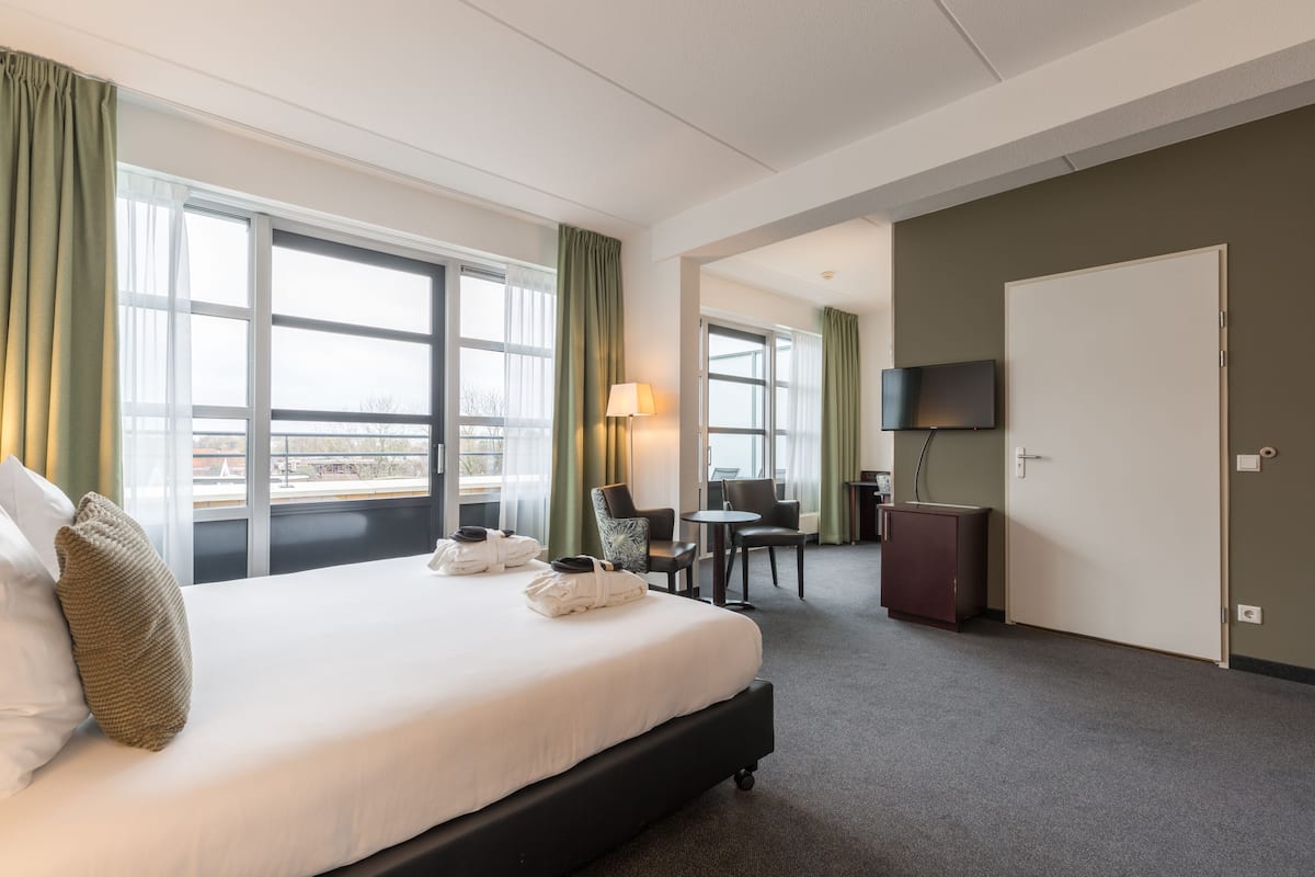 Une chambre d’hôtel avec un grand lit, un bureau, une chaise, une télévision et une armoire.