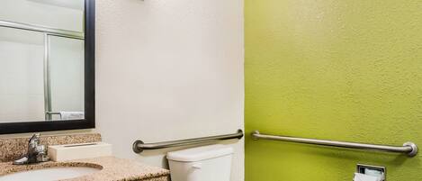 Un baño con lavamanos de granito, inodoro blanco y pared verde.