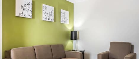 A living room with a beige sofa, a matching armchair, a coffee table, and three wall-mounted artworks.