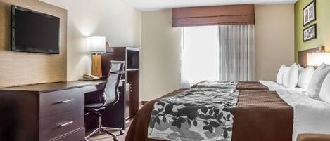 Habitación de hotel con cama, escritorio, silla, televisor y ventana con cortinas.