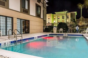 A swimming pool with a tiled edge, a metal ladder, and a chair.