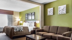 Une chambre d’hôtel avec un lit, un canapé, une table et des œuvres d’art accrochées aux murs.