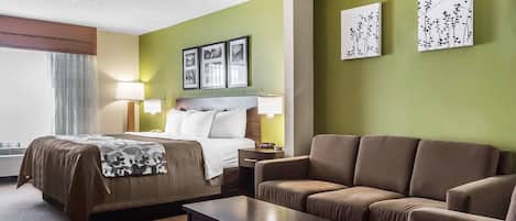 Una habitación de hotel con una cama, un sofá, una mesa y obras de arte en las paredes.