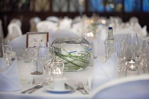 A table set for a formal event with numbered place cards, clear glassware, and a decorative glass bowl with green elements.