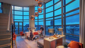 Een moderne hotelkamer met grote ramen, een eethoek en een zithoek.