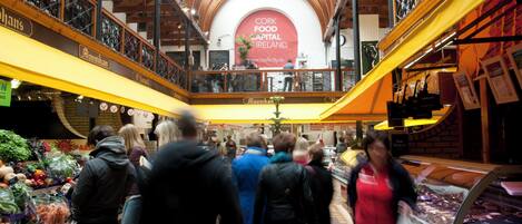 A bustling indoor market with a central archway displaying "Cork Food Capital Ireland".
