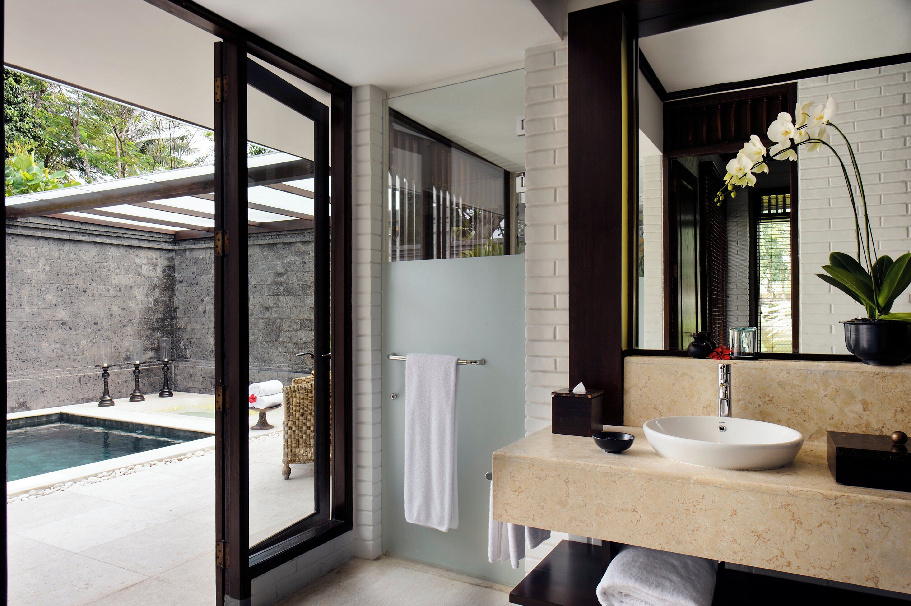 A modern bathroom with a large window, a sink, and a mirror.