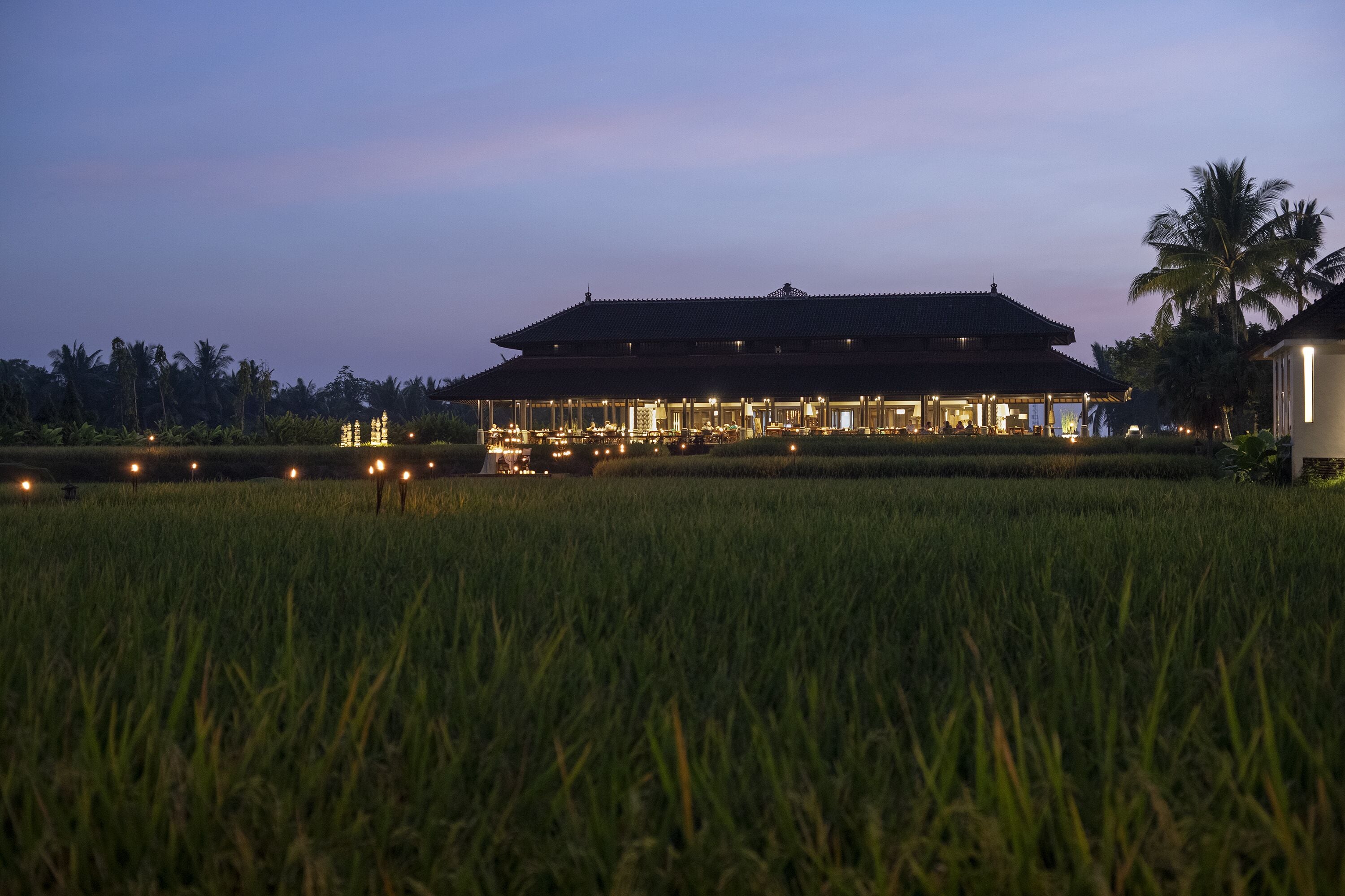 A traditional building with a tiled roof, surrounded by a well-maintained lawn and palm trees.