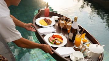 A dining setup on a boat with plates of food, drinks, and a bottle of champagne.