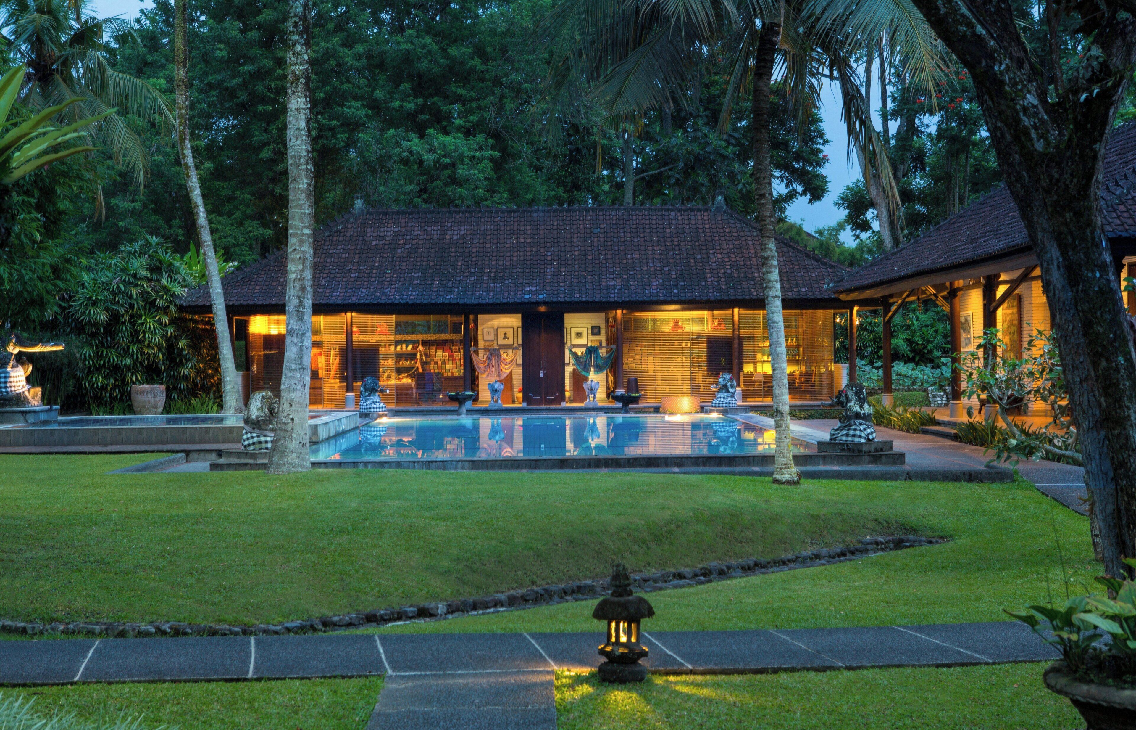 Un resort con piscina, rodeado de vegetación tropical y un césped bien cuidado.