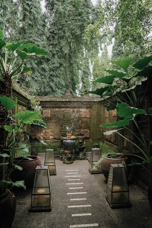 A courtyard with a central stone structure surrounded by potted plants and lanterns. - Tanah Gajah, a Resort by Hadiprana (Ubud)