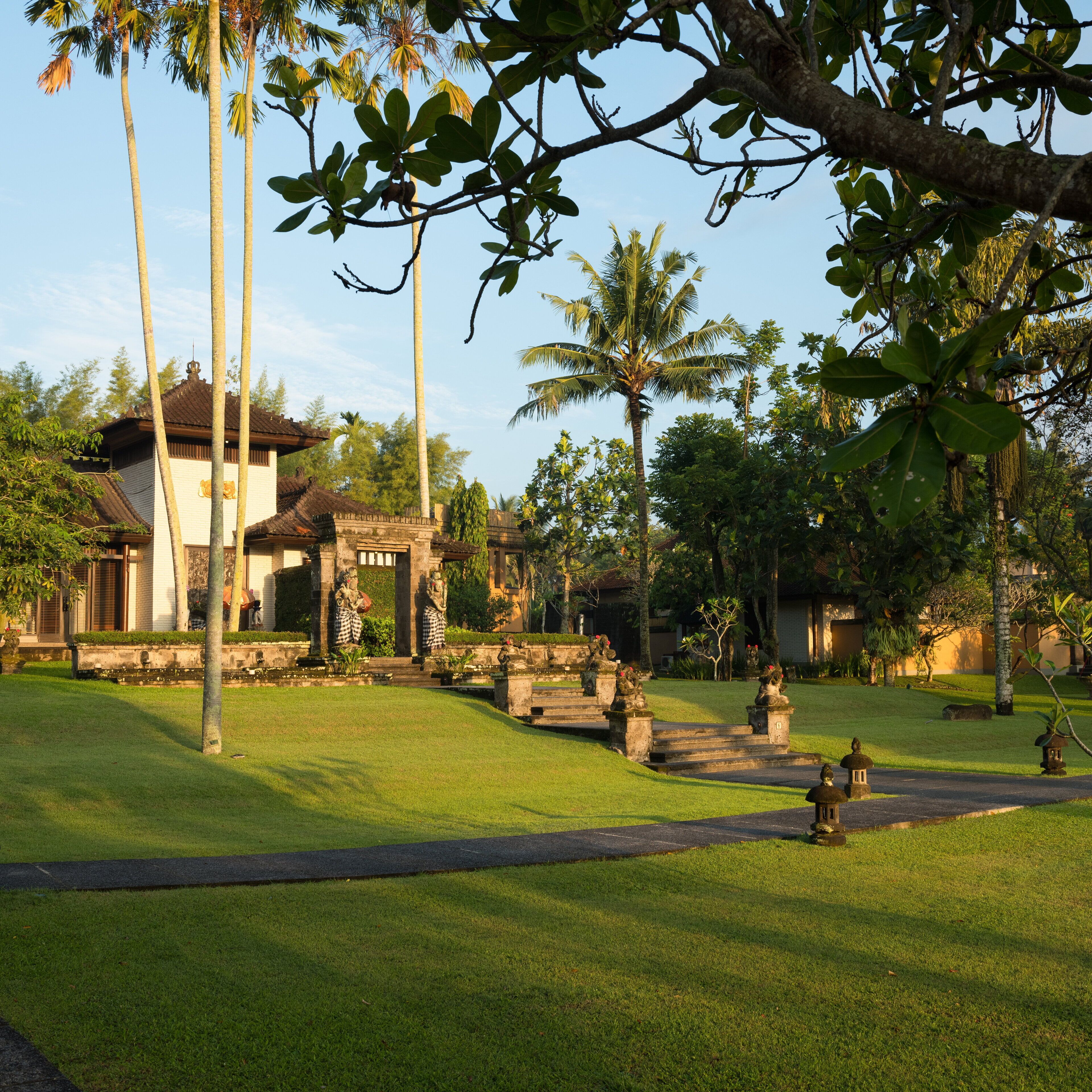 A traditional building with a tiled roof, surrounded by a well-maintained lawn and palm trees.