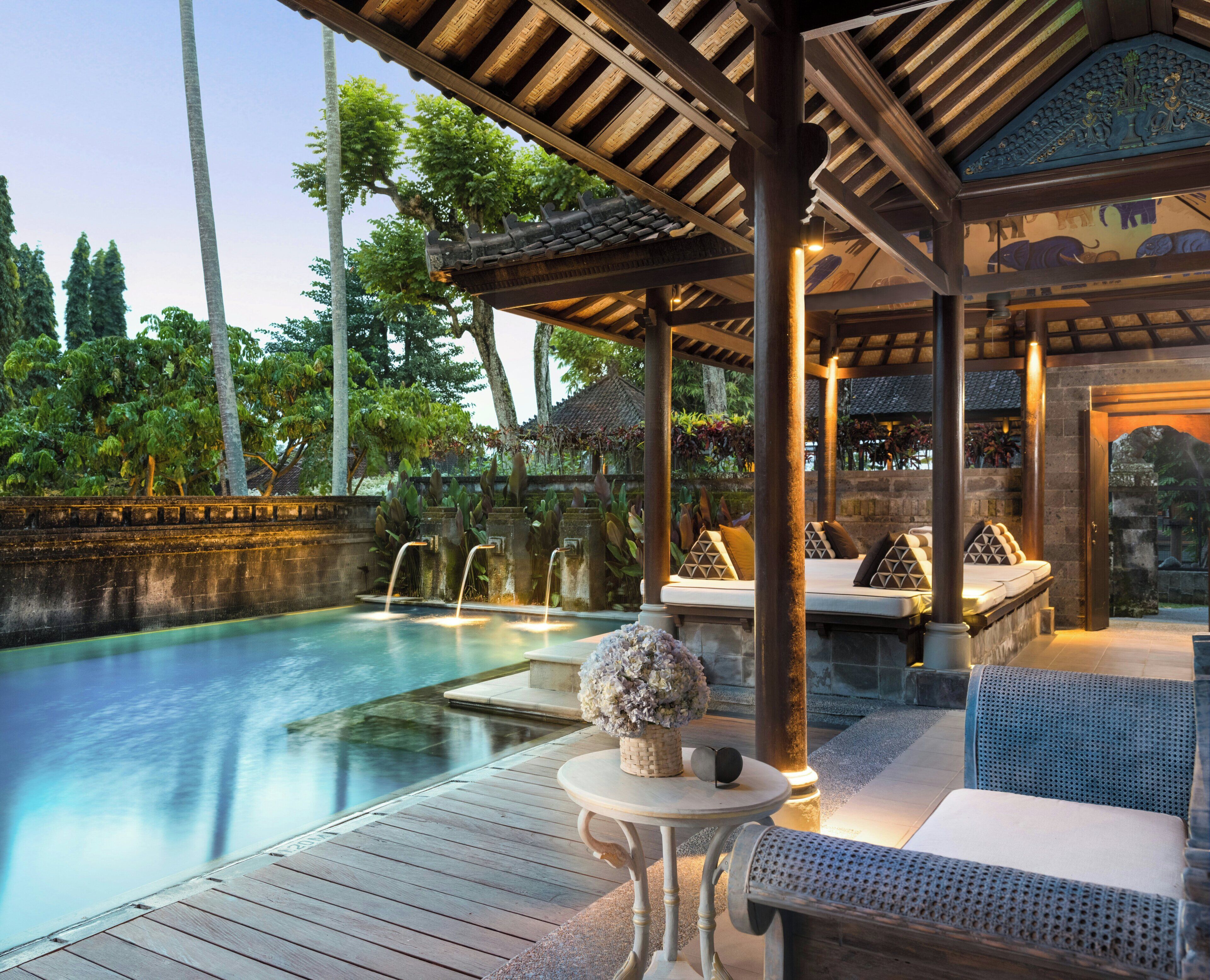 Un espace aménagé au bord de la piscine, avec une terrasse en bois, des chaises longues et un élément décoratif central.