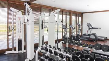 A gym with various exercise equipment, including dumbbells, a treadmill, and weight machines.