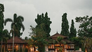 A traditional-style building with a tiled roof, surrounded by lush greenery and tall trees. - Tanah Gajah, a Resort by Hadiprana (Ubud)
