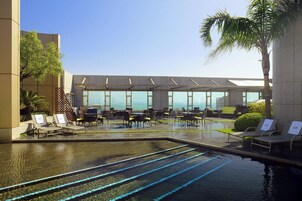 A pool area with lounge chairs and a seating area with a view of the ocean.