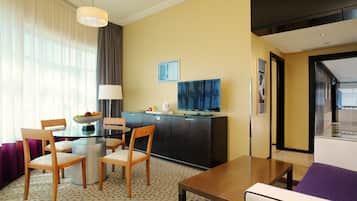 Hotelkamer met een zithoek, een bank, een televisie en een minibar.