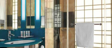 A modern bathroom with a glass-enclosed shower, a sink with a blue countertop, and a mirror with vertical light strips.