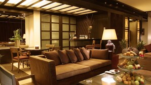 A modern hotel lobby with a sofa, chairs, a dining table, and a fruit display. - Four Points by Sheraton Le Verdun (Beirut)