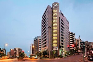 Un hotel alto con un llamativo letrero de 'Four Points by Sheraton', varios pisos y un diseño arquitectónico moderno.