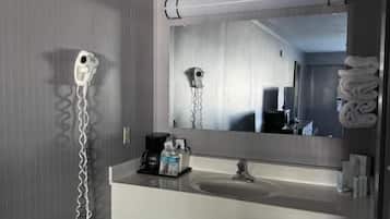 A modern bathroom with a white sink, a mirror, a hairdryer, and a towel rack.