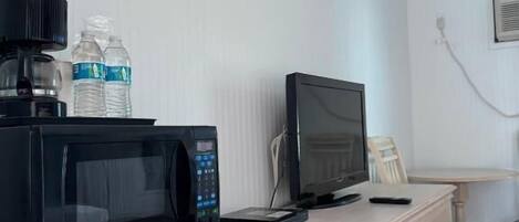 Une petite cuisine équipée d’un four à micro-ondes, d’un petit réfrigérateur, d’une télévision et d’une commode en bois.