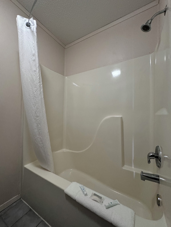Un baño moderno con bañera, ducha y toallero con artículos de aseo.